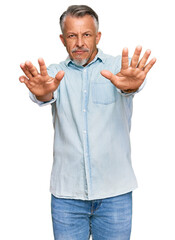 Naklejka premium Middle age grey-haired man wearing casual clothes doing stop gesture with hands palms, angry and frustration expression