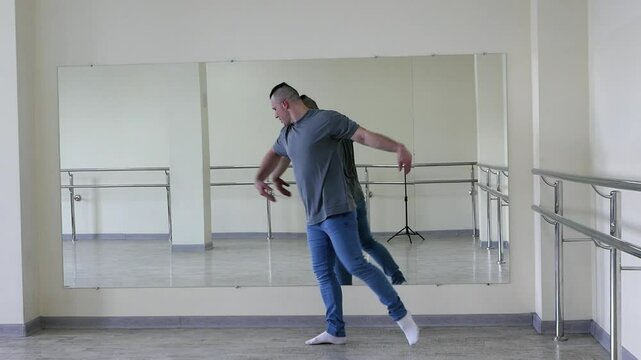 Male dance ballet in the hall, a man dances in the fitness room. A handsome young guy makes simple dance movements.