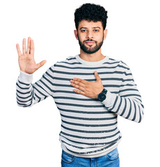 Young arab man with beard wearing casual striped sweater swearing with hand on chest and open palm,...