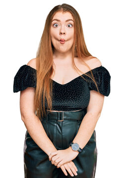 Young beautiful redhead woman wearing elegant clothes making fish face with lips, crazy and comical gesture. funny expression.