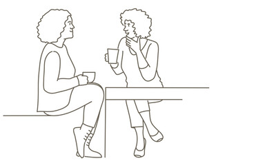 Two women are sitting at a table, one of them is holding a cup