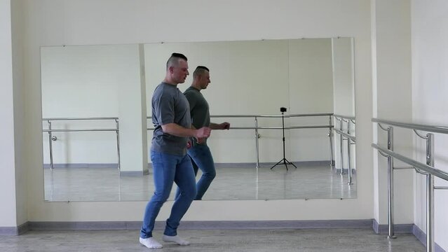 Male dance choreography ballet in the hall, a man dances in jeans in the fitness room. A handsome young guy makes simple dance movements.