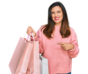 Beautiful hispanic woman holding shopping bags smiling happy pointing with hand and finger