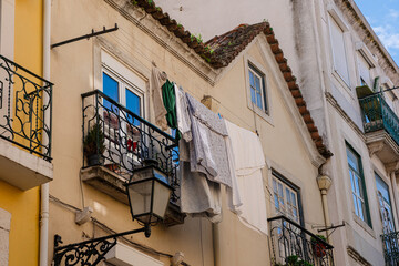 Street of Lisbon city. Washed clothes hang from the balcony and dry outside. Clothes dry on the balcony, old vintage houses, authentic architecture