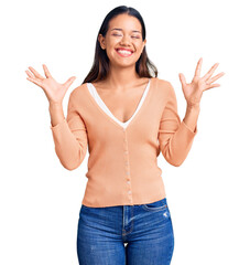 Young beautiful latin girl wearing casual clothes celebrating mad and crazy for success with arms...
