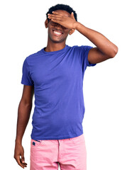 African handsome man wearing casual clothes and glasses smiling and laughing with hand on face covering eyes for surprise. blind concept.