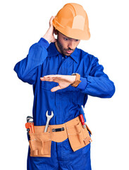 Young hispanic man wearing worker uniform looking at the watch time worried, afraid of getting late