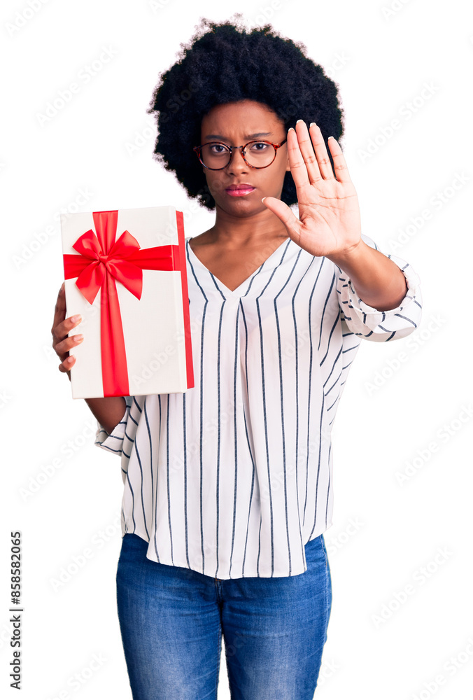 Wall mural young african american woman holding gift with open hand doing stop sign with serious and confident 