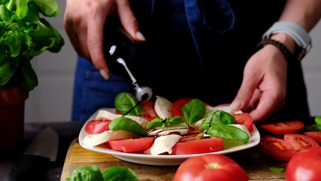 Woman Pouring Balsamic Sauce Over Fresh Veggie Caprese Salad In The Kitchen