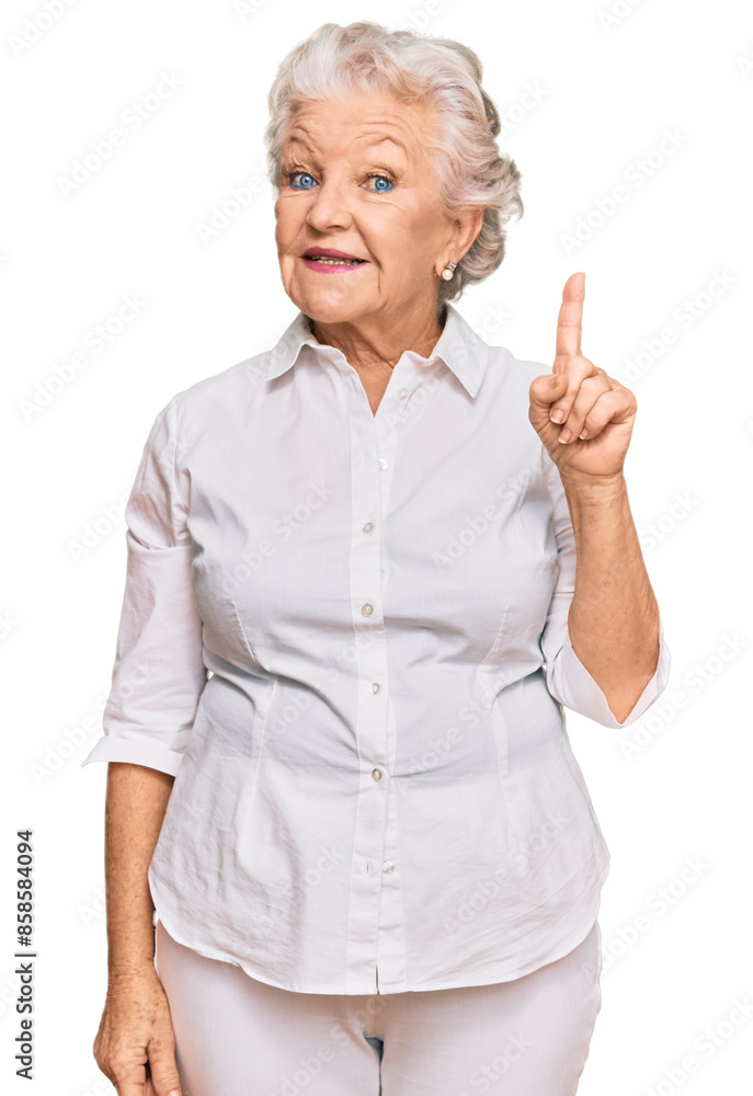 Wall mural Senior grey-haired woman wearing casual clothes showing and pointing up with finger number one while smiling confident and happy.