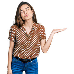 Young caucasian girl presenting with open palms, holding something looking at the camera blowing a kiss being lovely and sexy. love expression.