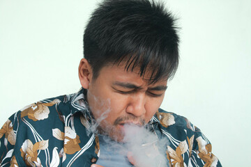 Isolated Asian young man coughing after use e-cigarette or vape. Unhealthy living concept.