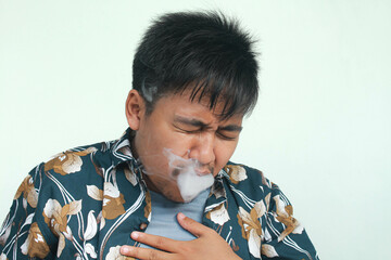 Isolated Asian young man coughing after use e-cigarette or vape. Unhealthy living concept.