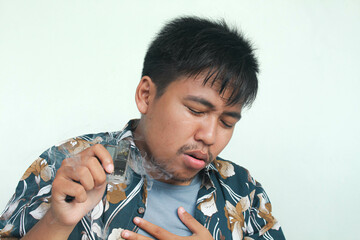 Isolated Asian young man coughing after use e-cigarette or vape. Unhealthy living concept.