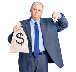 Senior grey-haired man wearing business suit holding money bag with dollar symbol with angry face,...