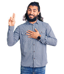 Young arab man wearing casual clothes smiling swearing with hand on chest and fingers up, making a...