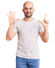 Young handsome man wearing casual t shirt showing and pointing up with fingers number seven while smiling confident and happy.