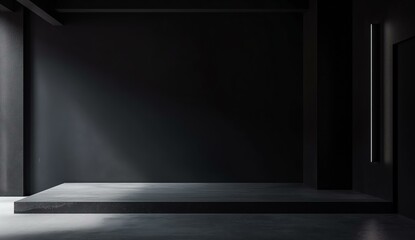 Obraz premium A minimalist dark room with a concrete floor and walls, illuminated by a spotlight casting soft shadows. The room has an elevated platform, creating a distinct stage-like appearance with a modern
