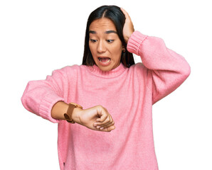 Young asian woman wearing casual winter sweater looking at the watch time worried, afraid of...