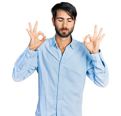 Hispanic man with blue eyes wearing business shirt relaxed and smiling with eyes closed doing meditation gesture with fingers. yoga concept.