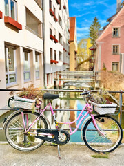 Fototapeta premium Pink Bicycle Standing In Front Of Beautiful Ulm Cityscape Reflection, Germany
