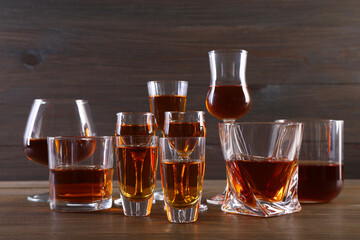 Different delicious liqueurs in glasses on wooden table