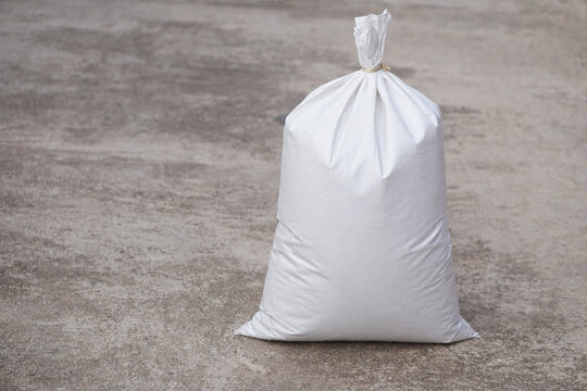 White polypropylene sack that contain full of agricultural grains, tied on the top with bamboo rope. Concept, reusable bag for contain crops, fertilizer or others.         