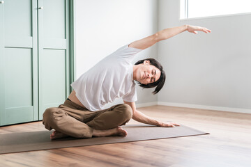家で柔軟体操・体操・ストレッチする若いアジア人男性
