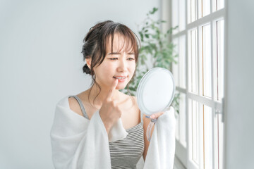 鏡で歯を見て困るアジア人女性（虫歯・歯並び・歯周病）
