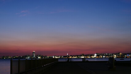 Night view of a lit-up seaside town. people watching. (silhouette, copy space)