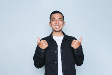Asian young man smiling happy at the camera and give thumb up.