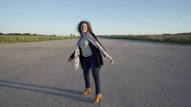Mujer alegre paseando por una pista de aterrizaje porque se va de viaje en avi&oacute;n.