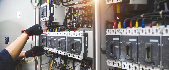 Electricity and electrical safety maintenance service system, Technician hand checking electric current voltage at circuit breaker terminal and cable wiring in main power distribution board.