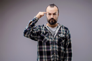 Bearded man pointing finger at head thinking hard
