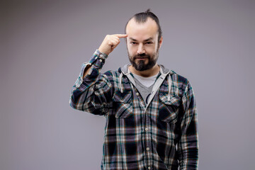 Bearded man pointing to his temple is thinking hard