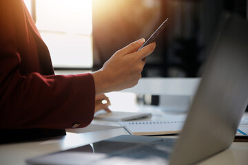 Naklejka premium Asian businesswoman in formal suit in office happy and cheerful during using smartphone and working