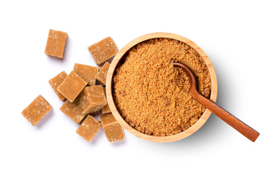 Brown unrefined cane sugar in wooden bowl and sugarcane cubes isolated on white background, top view, flat lay.