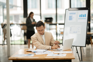 Asia business working on digital tablet executives meeting in an office using laptop...