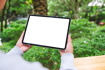 Mockup image of a woman holding digital tablet with blank white desktop screen in the outdoors