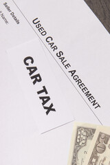 Obraz premium Inscription car tax, dollar banknotes and vehicle sales agreement. Sales, purchases, taxation of automobile