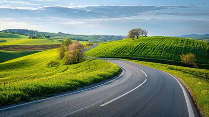 Highway beside vibrant green hills and fields in a spring landscape