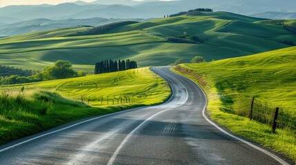 Highway beside vibrant green hills and fields in a spring landscape