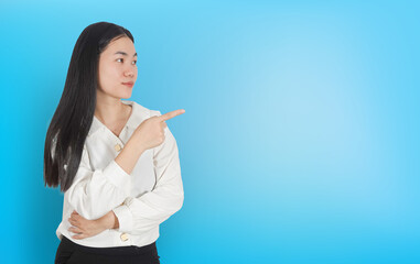 Young asian business woman with hand gesture pointing on blue background