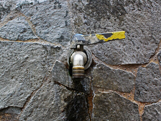 Close-up of a faucet installed on the stone wall. 