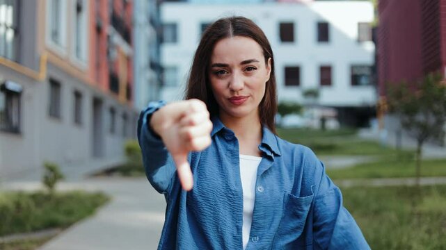 Unhappy young woman expresses disapproval with two thumbs down
