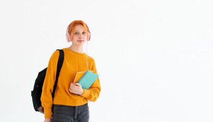 Young college going european redhead hair female nerd student with a backpack, headphones on head,...
