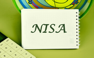 The word Nippon Individual Savings Account. NISA on a notepad on the background of a clock next to...