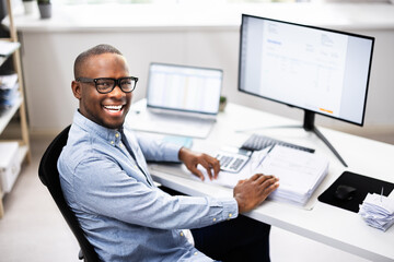 Top African-American Tax Advisor Smiling While Multitasking at His Desk