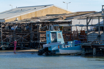 An old metal fishing boat docked near the seafood restaurant's outdoor terrace in the oyster farm village in southern France.