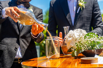 Two men in suits are pouring sand into a jar